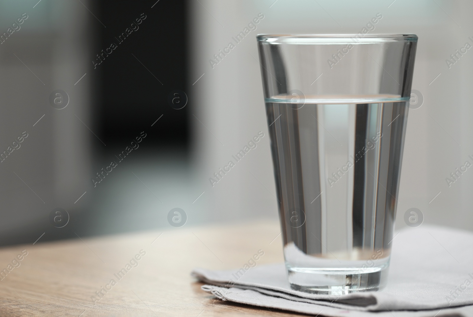 Photo of Glass of pure water on table against blurred background, space for text