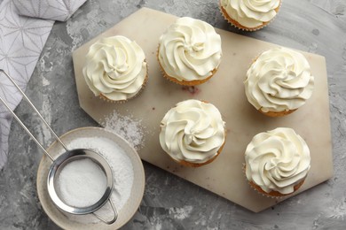 Photo of Tasty cupcakes with vanilla cream on grey table, top view