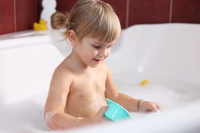 Photo of Little girl bathing in tub at home