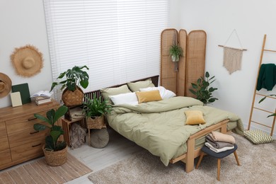 Photo of Stylish bedroom with comfortable bed and beautiful green houseplants, above view. Interior design