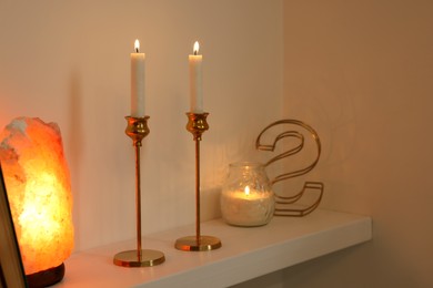 Photo of Pair of beautiful candlesticks, scented candle and salt lamp on white shelf, space for text