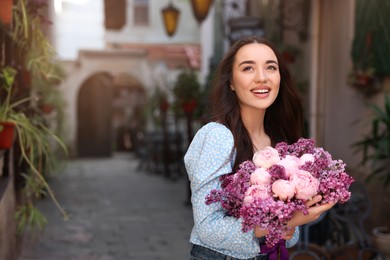 Photo of Beautiful woman with bouquet of spring flowers outdoors, space for text