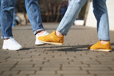 Photo of People greeting each other by bumping feet instead of handshake outdoors, closeup