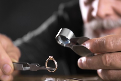 Photo of Male jeweler evaluating diamond ring in workshop, closeup view