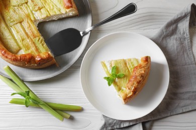 Freshly baked rhubarb pie and stalks on white wooden table, flat lay
