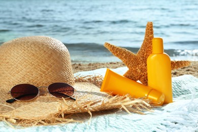 Photo of Sun protection products and beach accessories on blanket near sea