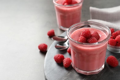 Photo of Delicious raspberry mousse served on grey table, space for text
