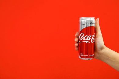 Photo of MYKOLAIV, UKRAINE - NOVEMBER 14, 2018: Woman holding Coca-Cola can on color background. Space for text