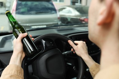 Photo of Man with bottle of beer driving car, closeup. Don't drink and drive concept