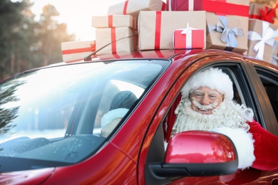 Photo of Authentic Santa Claus driving car with gift boxes, view from outside