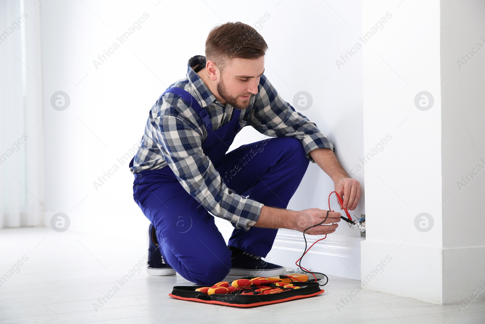 Photo of Professional electrician with tester checking voltage indoors