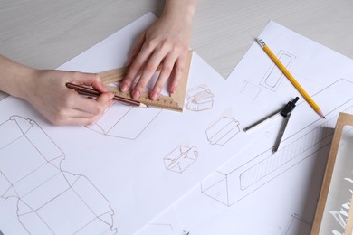 Photo of Woman creating packaging design at light wooden table, closeup