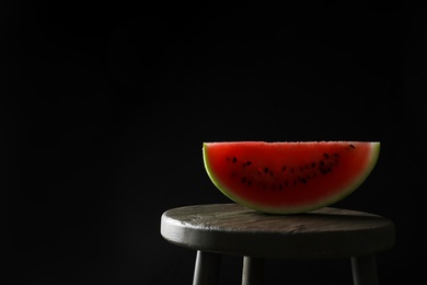 Photo of Slice of tasty fresh watermelon on table against black background, space for text