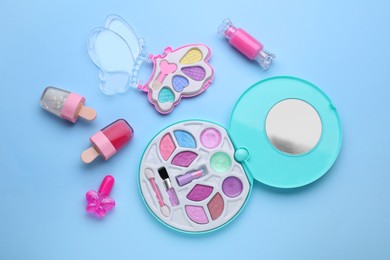 Photo of Eye shadow palette and other decorative cosmetics for kids on light blue background, flat lay