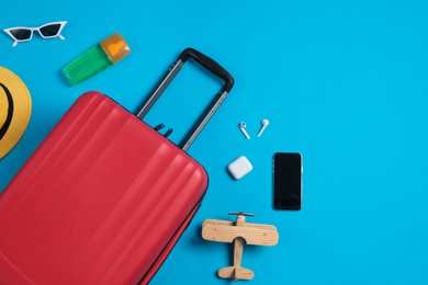 Photo of Flat lay composition with suitcase and travel accessories on light blue background. Summer vacation