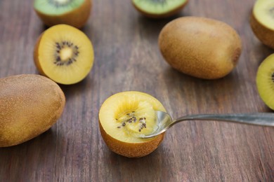 Photo of Spoon with half of kiwi and fruits on wooden table