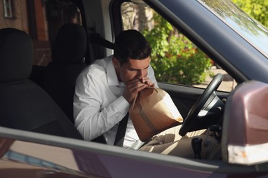 Photo of Man with paper bag suffering from nausea in car
