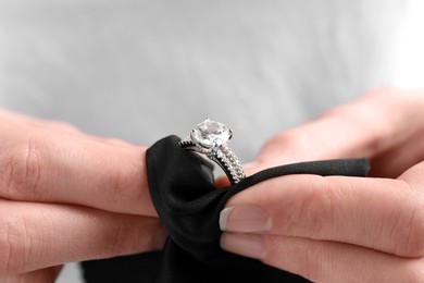 Photo of Jeweler cleaning diamond ring with microfiber cloth, closeup