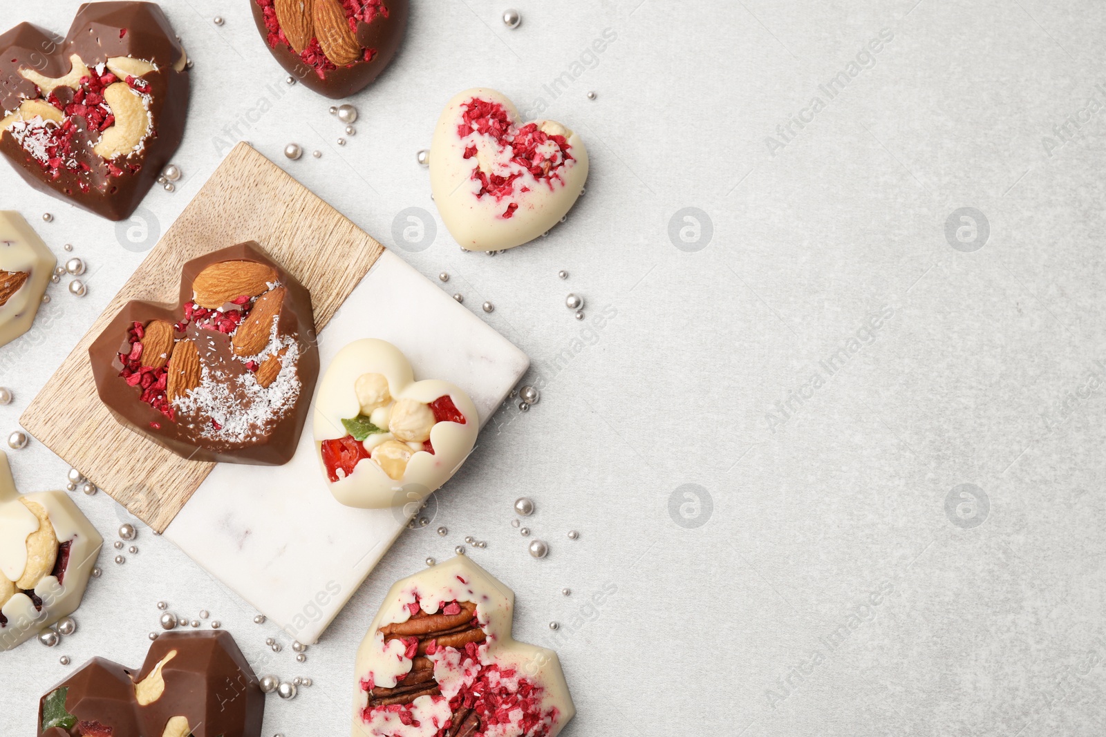 Tasty chocolate heart shaped candies with nuts on white table, flat lay. Space for text Photo of Tasty chocolate heart shaped candies with nuts on white table, flat lay. Space for text