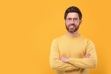 Photo of Portrait of handsome man in glasses on orange background, space for text