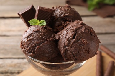 Photo of Tasty chocolate ice cream with mint in glass dessert bowl on table, closeup