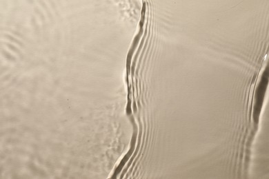 Photo of Rippled surface of clear water on beige background, top view