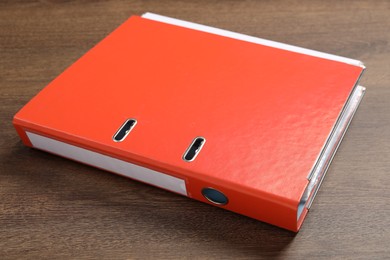 Photo of Orange hardcover office folder on wooden table, closeup