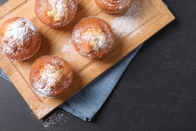 Photo of Delicious sweet muffins on black textured table, top view. Space for text