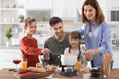 Photo of Happy family enjoying fondue dinner at home