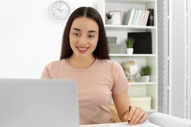 Photo of Home workplace. Happy woman working on laptop in room