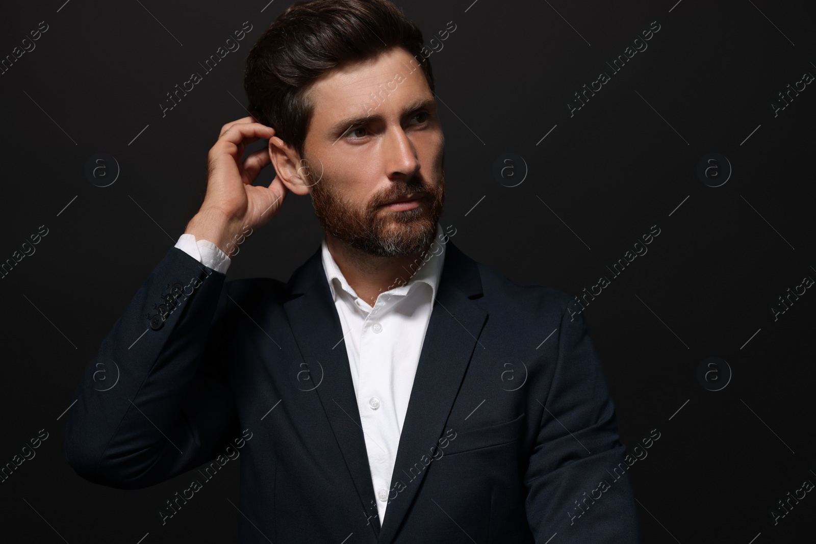 Photo of Portrait of handsome bearded man looking away on black background. Space for text