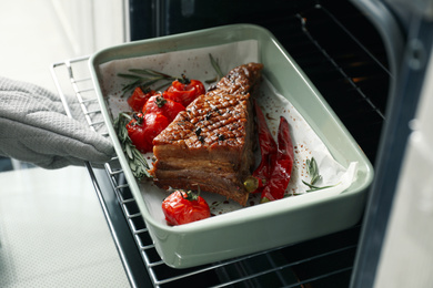Photo of Chef taking delicious roasted ribs out of oven, closeup
