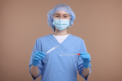 Photo of Laboratory testing. Doctor with cotton swab and tube on light brown background