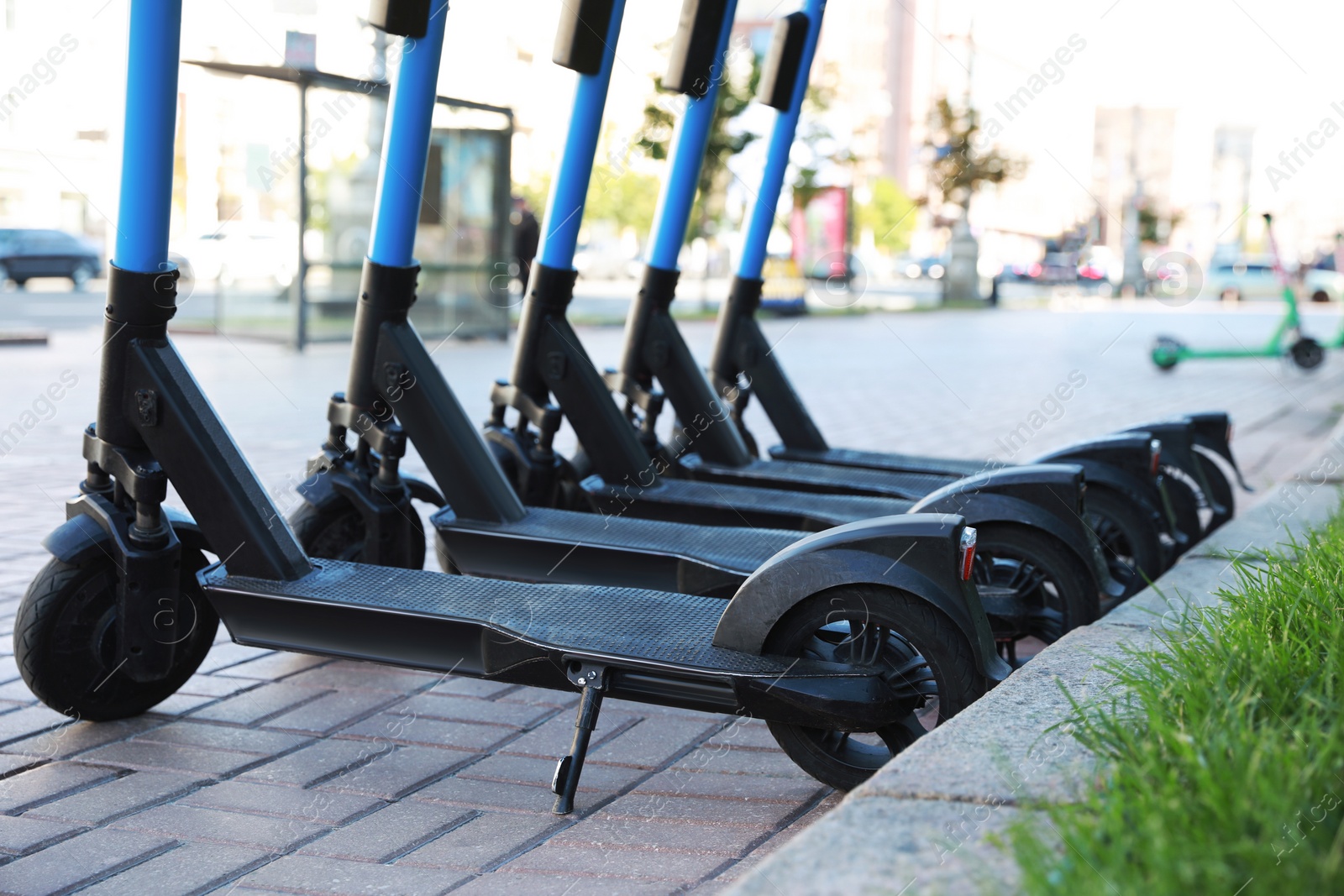 Photo of Many modern electric scooters parked on city street. Rental service