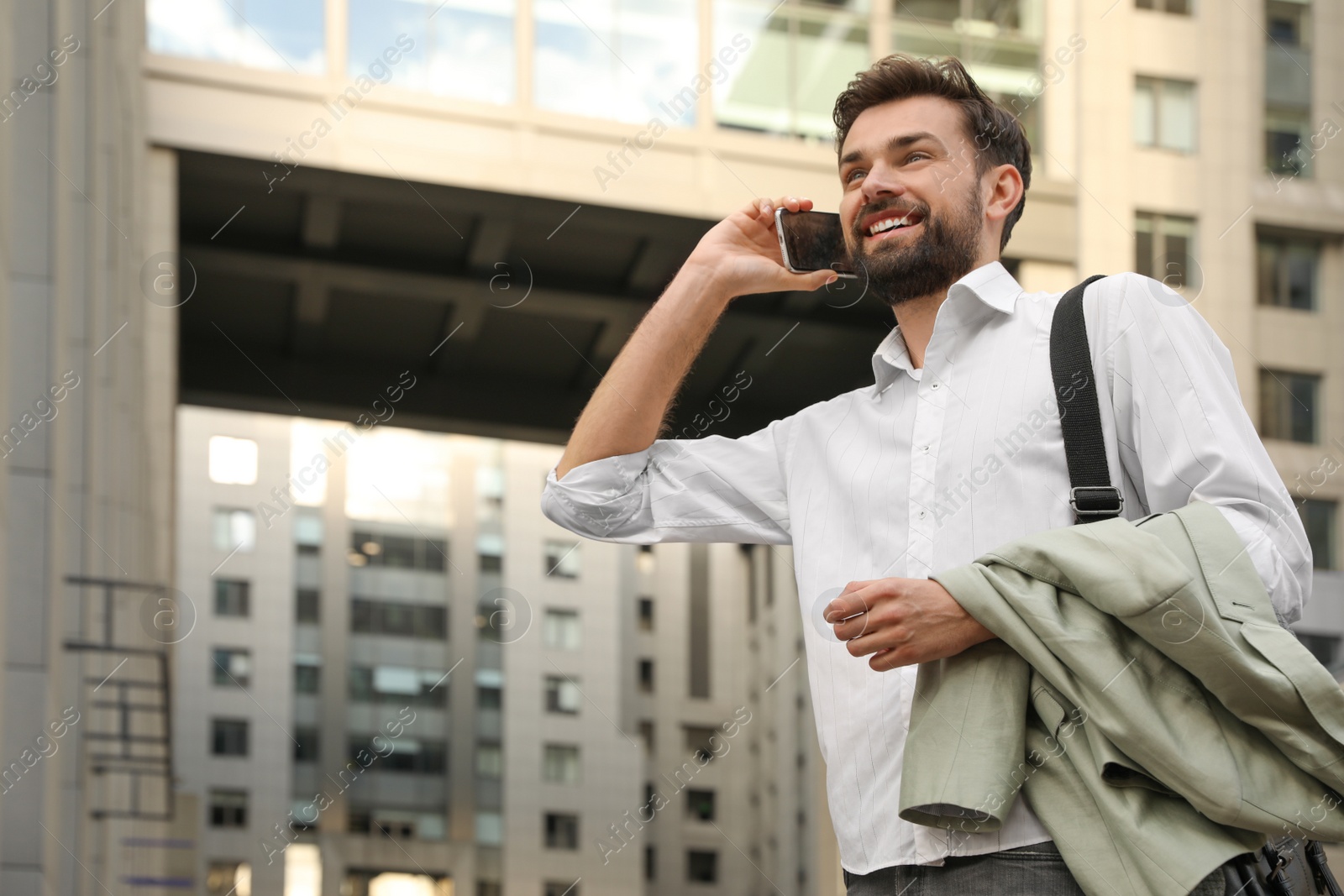 Photo of Handsome man talking on phone in modern city