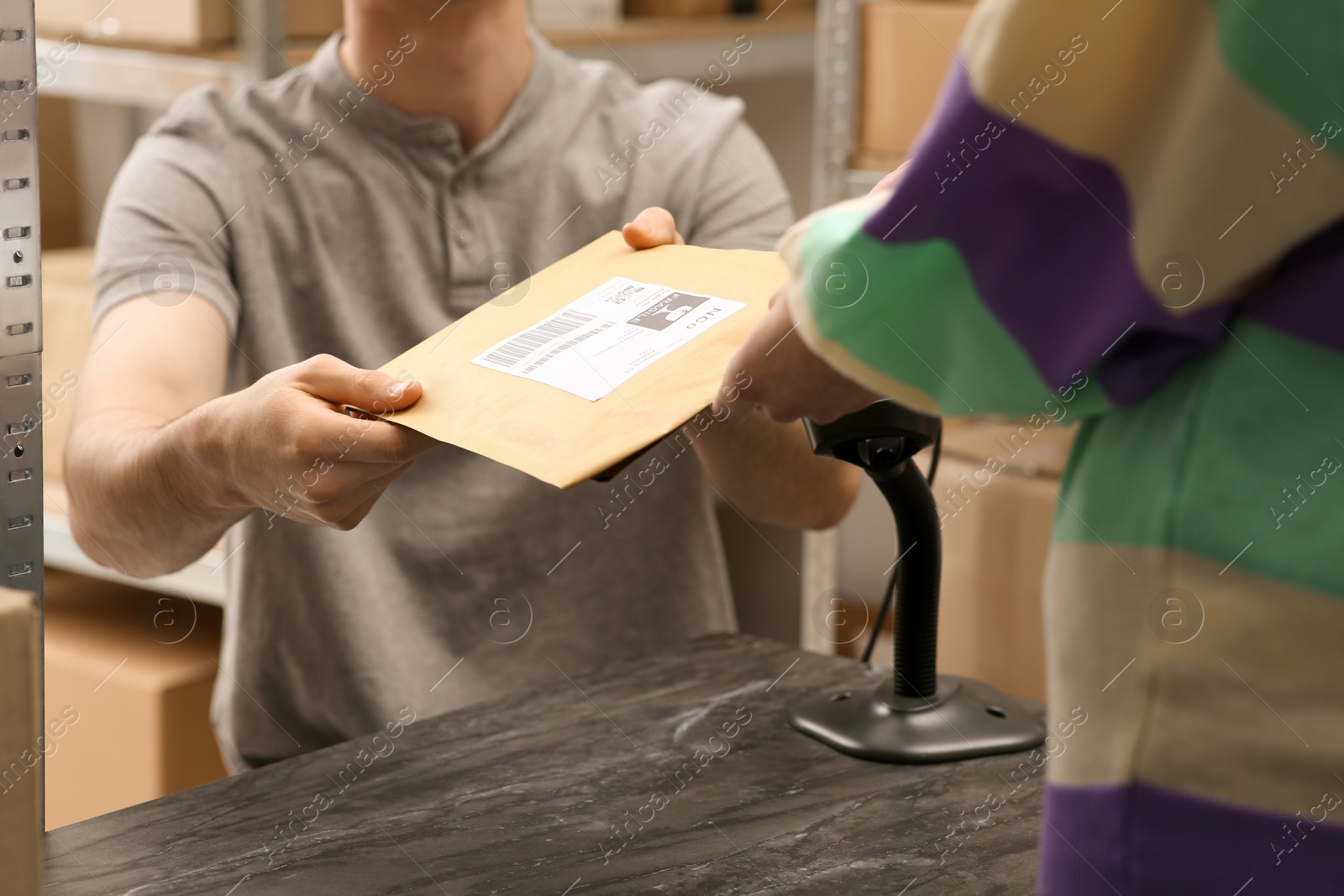 Photo of Worker giving parcel to woman at post office, closeup