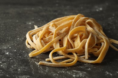 Photo of Uncooked homemade pasta on dark grey table, closeup