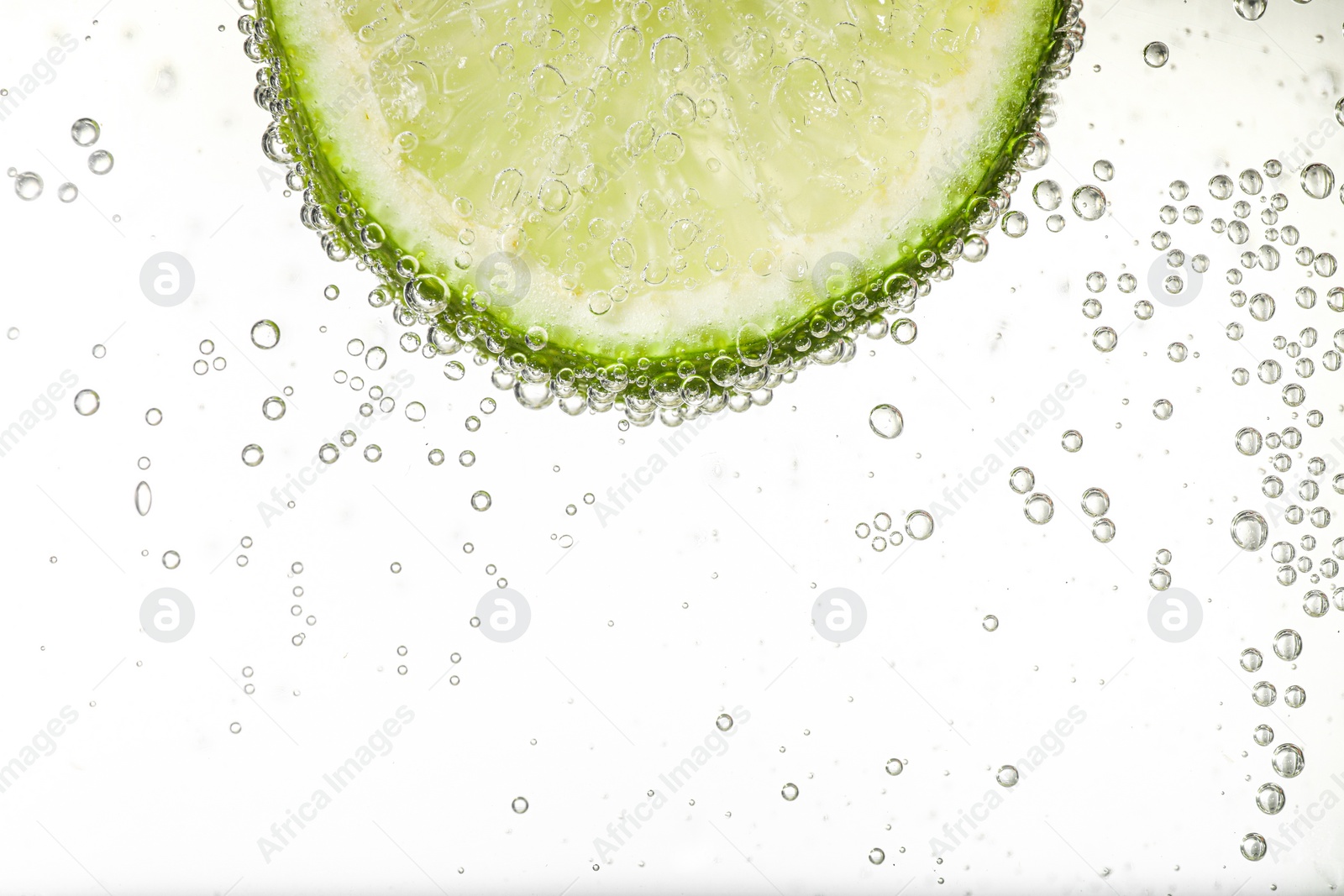 Photo of Juicy lime slice in soda water against white background, closeup. Space for text