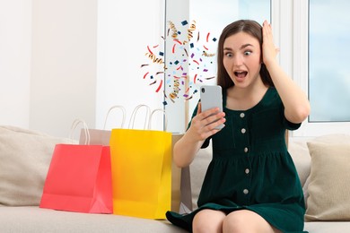 Image of Discount offer. Surprised young woman holding smartphone at home. Confetti and streamers near device