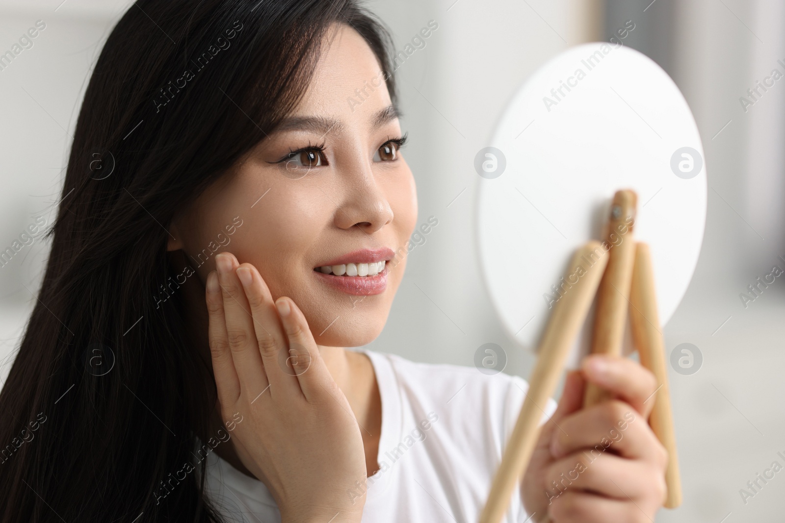 Photo of Woman with perfect skin looking at mirror indoors