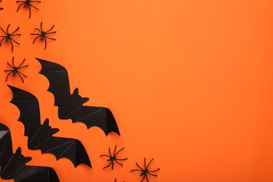 Photo of Flat lay composition with paper bats and spiders on orange background, space for text. Halloween celebration