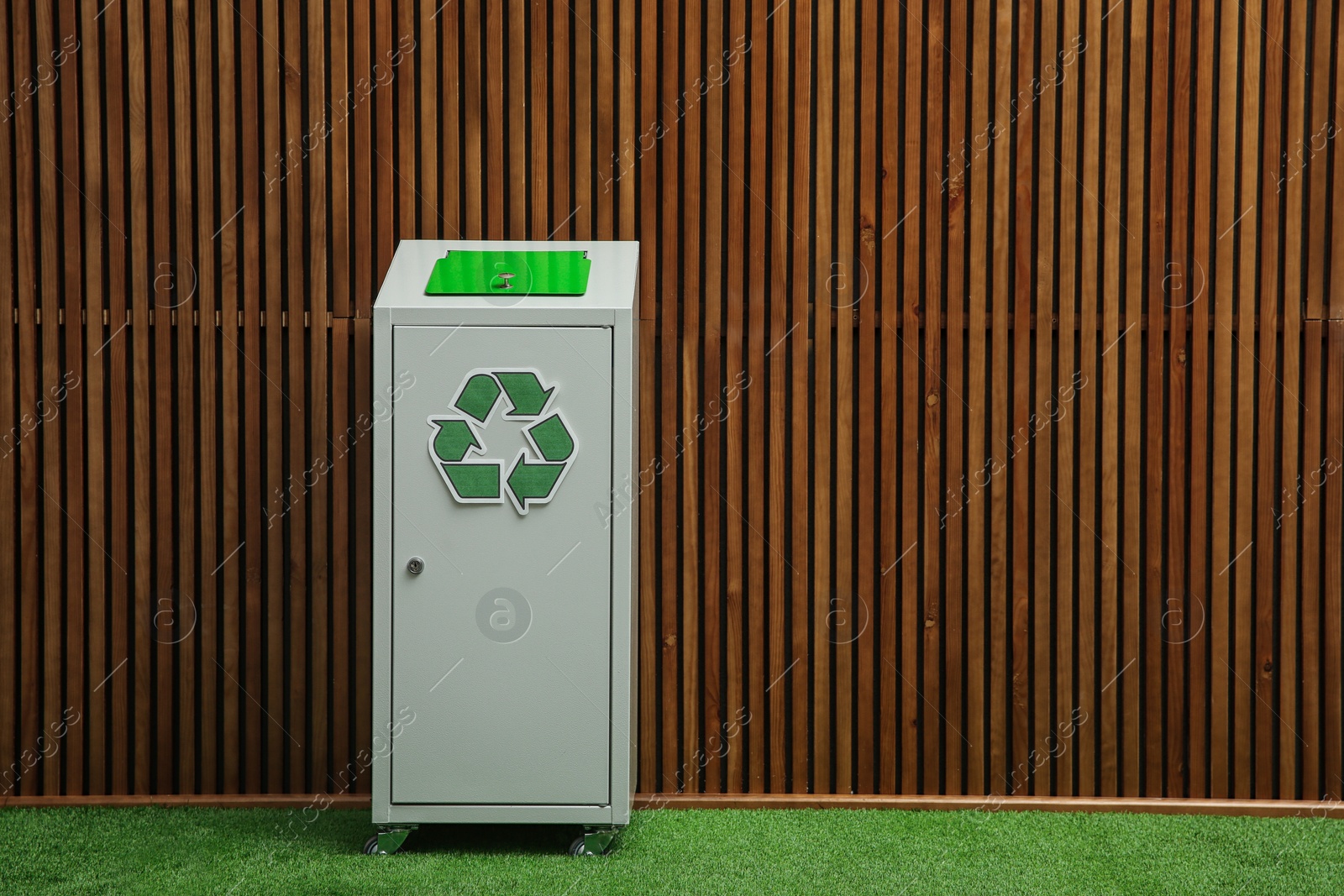 Photo of Trash bin with recycling symbol near wooden wall indoors. Space for text