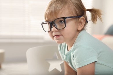 Photo of Cute little girl in glasses at home. Space for text