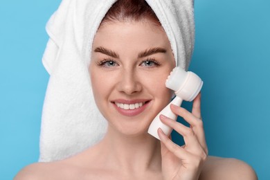 Photo of Washing face. Young woman with cleansing brush on light blue background