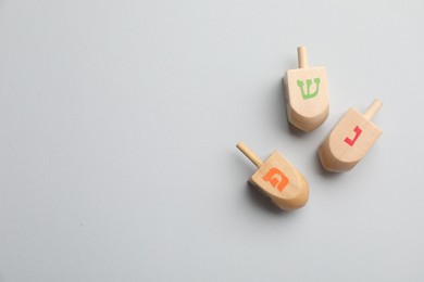 Wooden dreidels on white background, flat lay with space for text. Traditional Hanukkah game