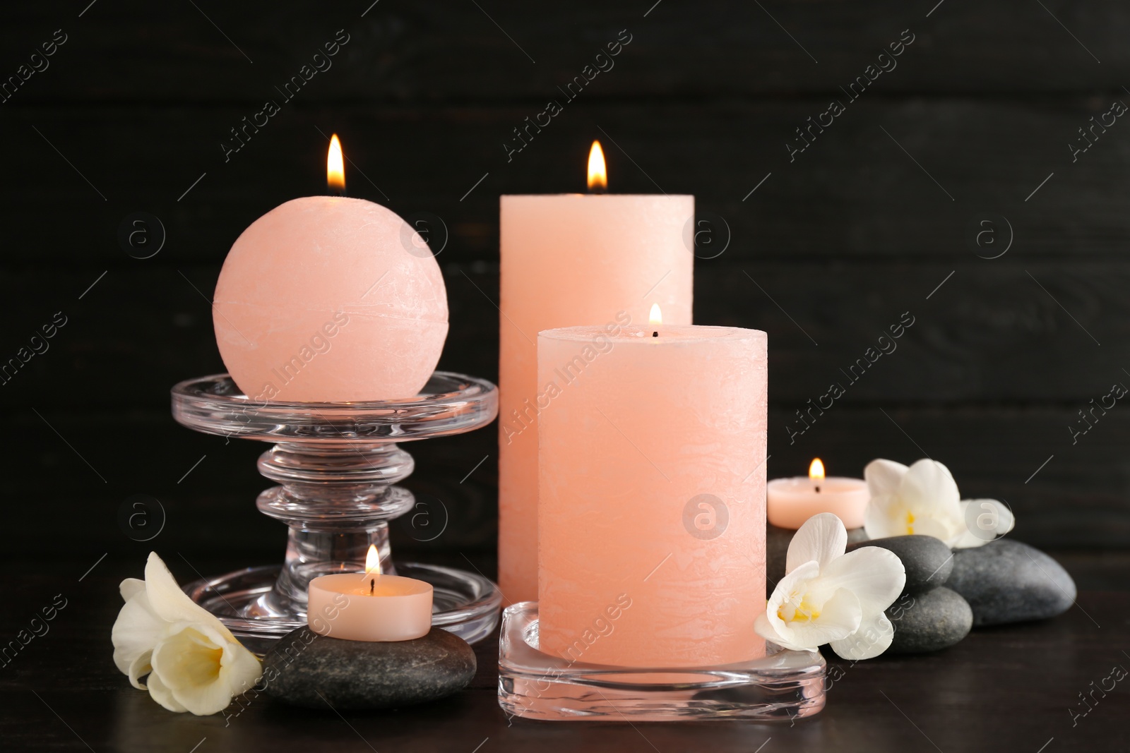 Photo of Composition of burning candles, spa stones and flowers on table