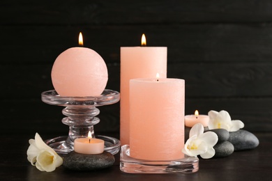 Composition of burning candles, spa stones and flowers on table