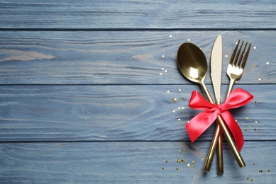 Photo of Cutlery set on blue wooden table, top view with space for text. Christmas celebration