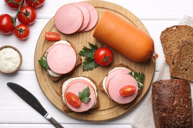 Photo of Delicious sandwiches with boiled sausage, tomato and sauce on white wooden table, flat lay