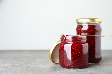 Jars of raspberry jam on grey table. Space for text